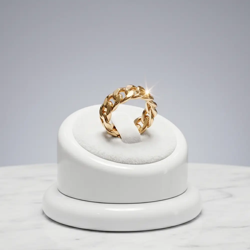 Anillo cubano oro laminado, en exhibidor blanco y fondo gris sobre superficie de marmol