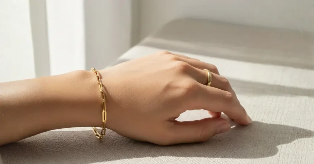 oro laminado no mancha, mano de mujer con manilla sobre una superficie gris