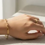 oro laminado no mancha, mano de mujer con manilla sobre una superficie gris