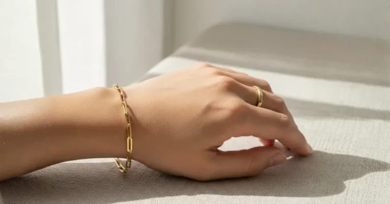 oro laminado no mancha, mano de mujer con manilla sobre una superficie gris