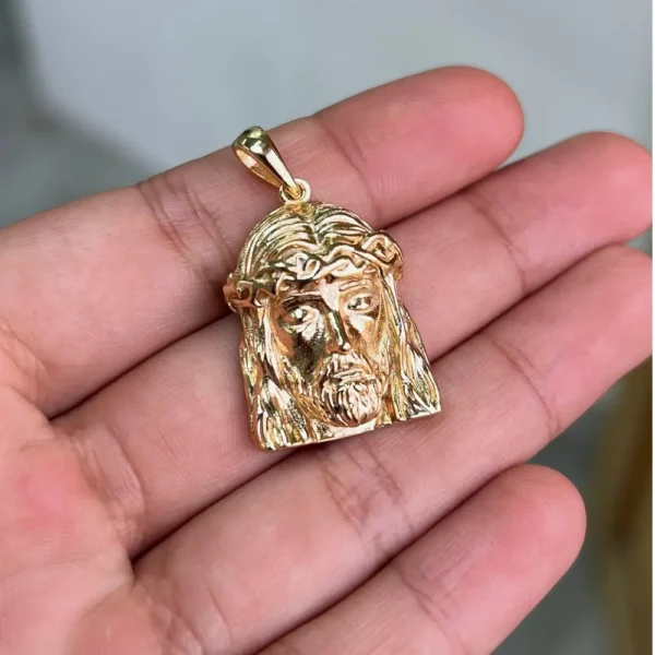 Dije Rostro de Jesús en oro laminado sobre la mano